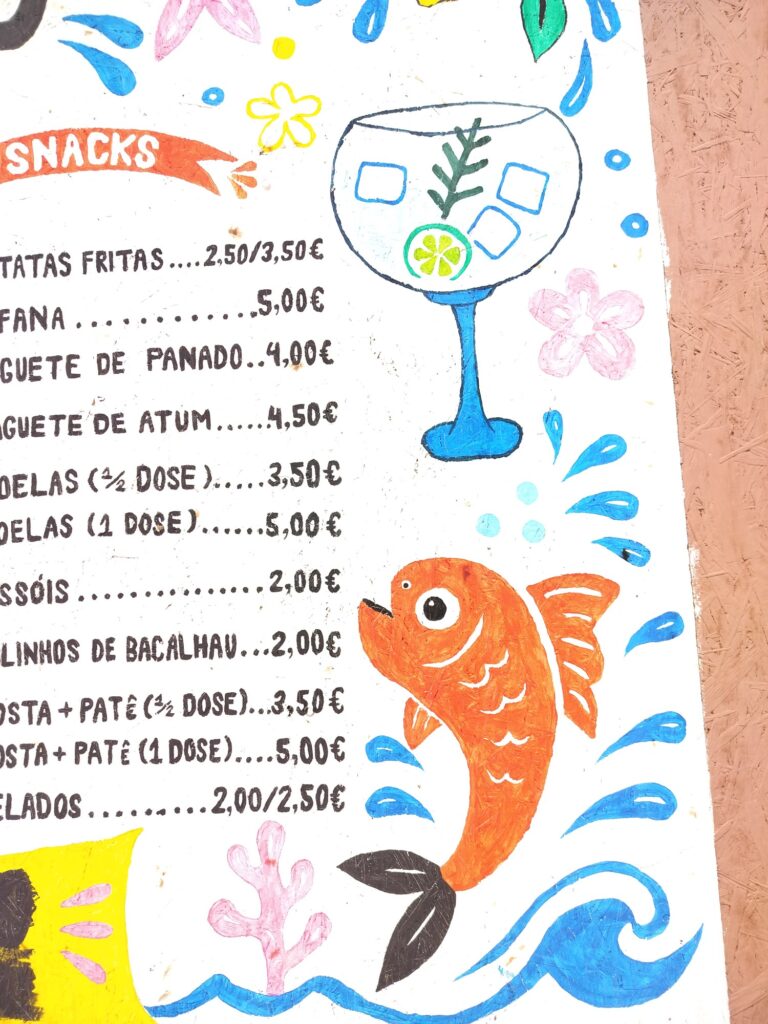 The painted board's snack list next to an orange fish with white scale marks and blue water splashes.